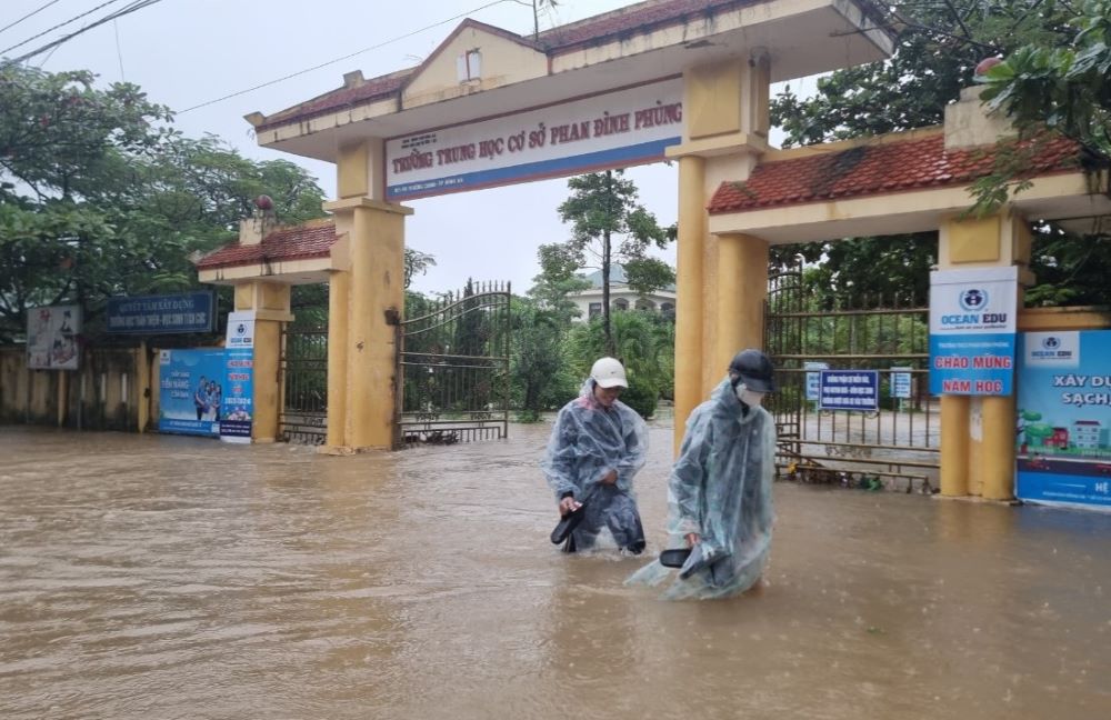 Học sinh lội bì bõm trong nước lũ. Ảnh: Hưng Thơ.