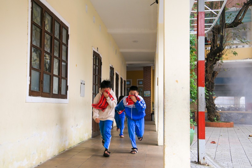 Học sinh dùng khăn bịt mũi tránh khói độc và cúi thấp người để chạy thoát nạn khỏi đám cháy.