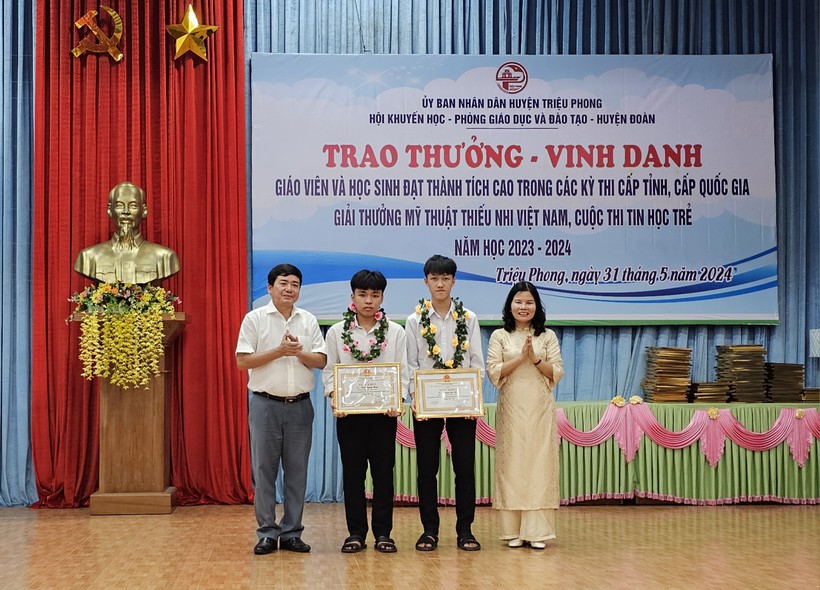 Ông Nguyễn Thành Vũ, Phó Chủ tịch UBND huyện và lãnh đạo Phòng GDTH-GDTX khen thưởng 2 học sinh đạt giải Nhất.