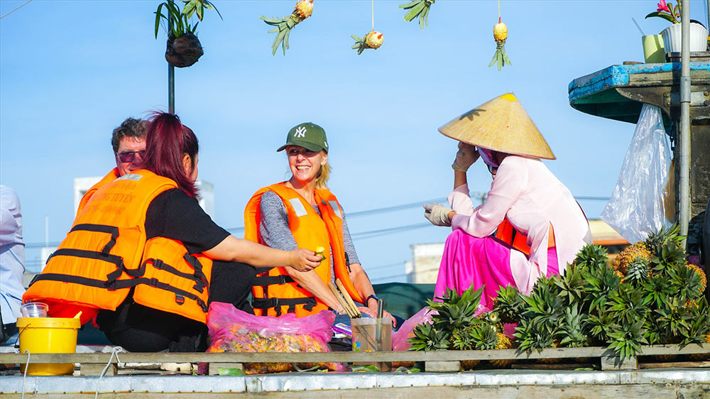 Du khách nước ngoài thưởng thức trái cây ở chợ nổi Cái Răng, Cần Thơ. Chợ nổi Cái Răng là điểm dừng phổ biến của khách quốc tế du lịch Việt Nam. Ảnh: Tạ Quang