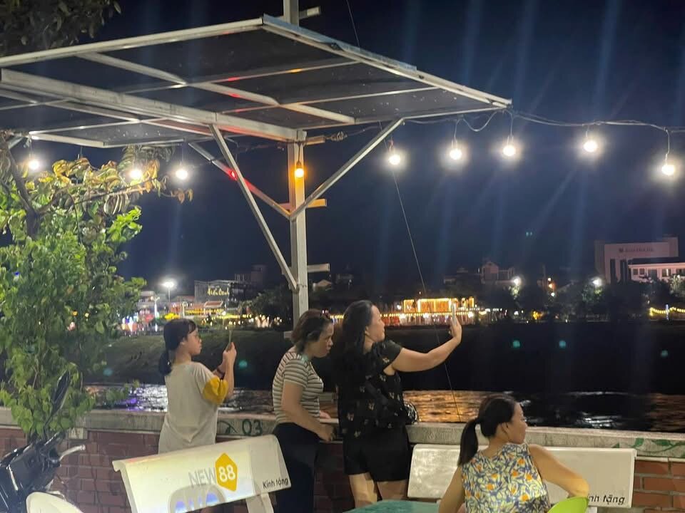 Người dân chụp ảnh check - in cùng cảnh sông về đêm. Ảnh: Anh Tâm