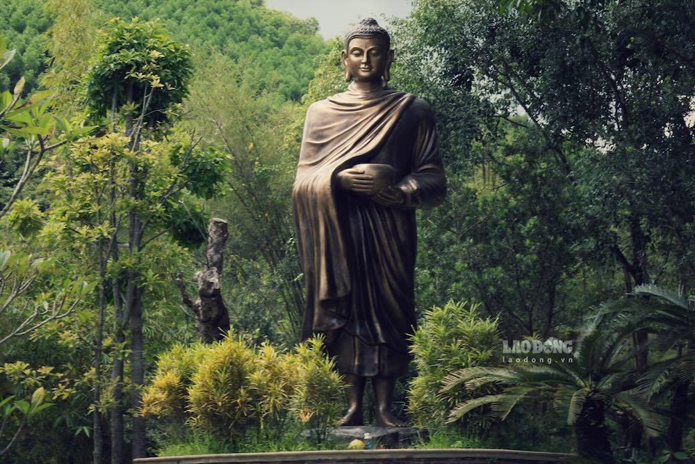 Tượng phật đứng, giữa đất trời bao la, bao quanh những rừng cây xanh mướt và núi non hùng vĩ.