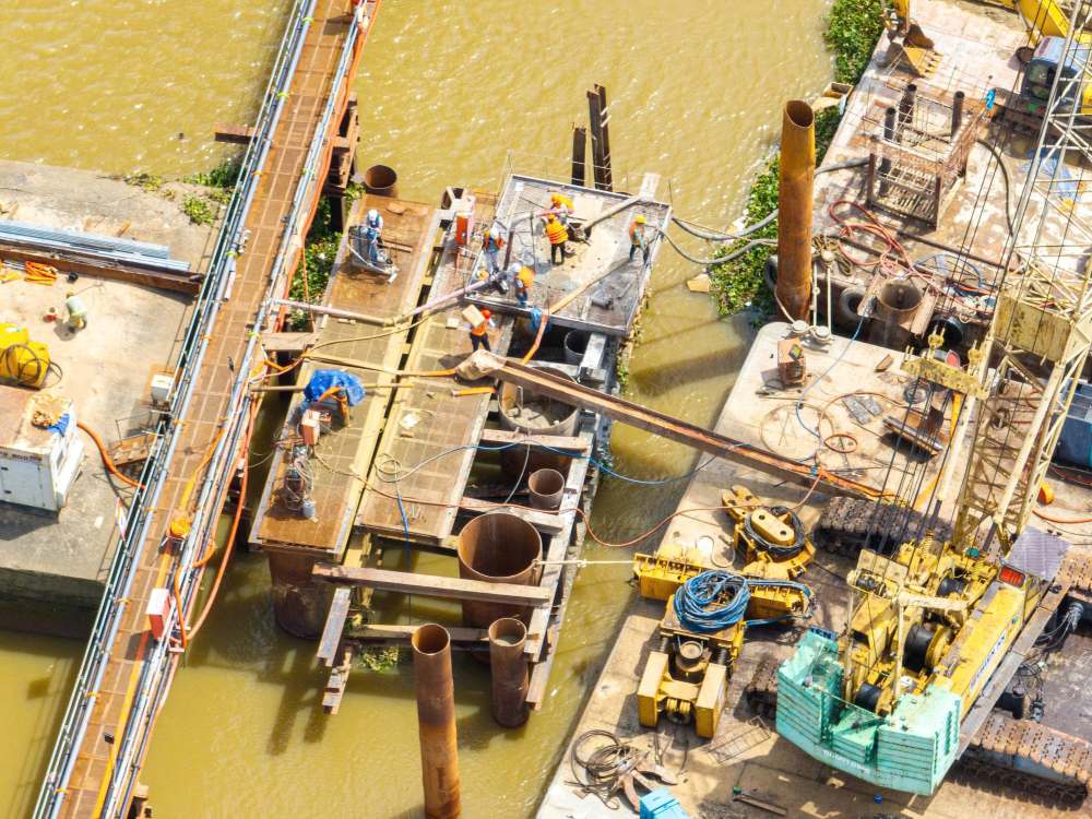 Tại công trường, các nhà thầu đang khoan cọc và đổ bê tông móng trụ giữa lòng sông. Đây là bước kỹ thuật đầu tiên của hạng mục mở rộng cầu. Ảnh: Nhâm Nguyễn