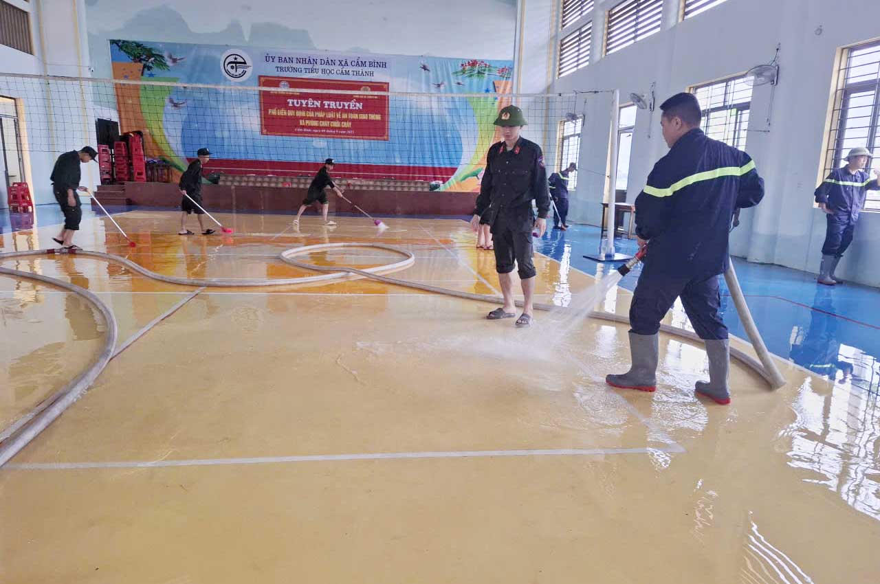 Công an dùng vòi phun mạnh dọn bùn tại Trường Tiểu học Cẩm Thành. Ảnh: Trần Tuấn.