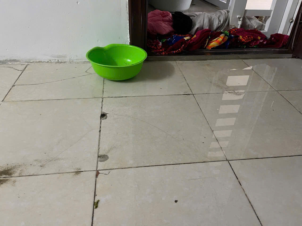 Do chung cư bị tốc mái dẫn đến thấm dột, người dân phải dùng chậu nhựa hứng nước mưa. Ảnh: Quang Đại