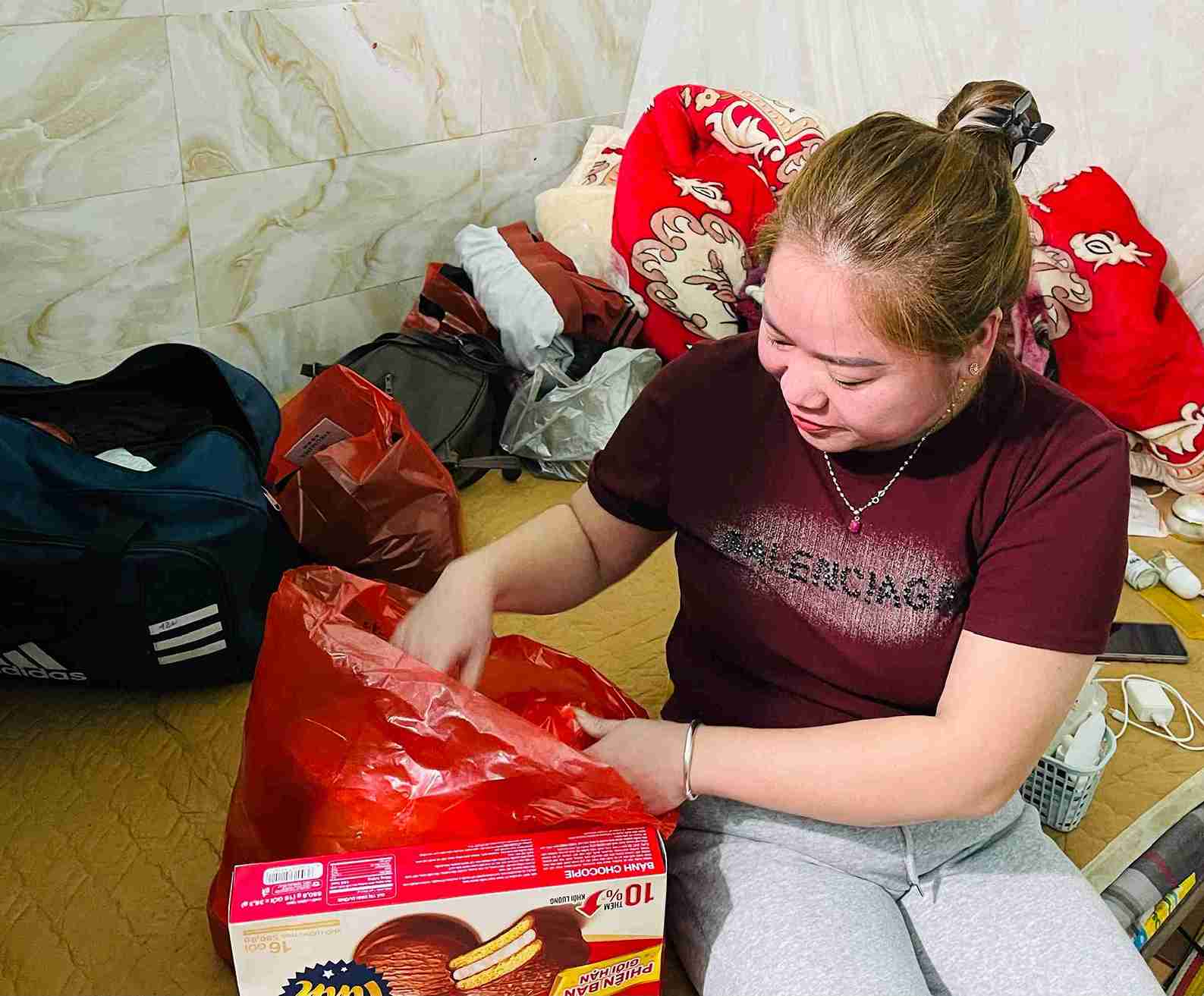 Chị Phương lặng lẽ chuẩn bị quần áo cho chuyến xe về quê sau một năm lao động xa nhà.