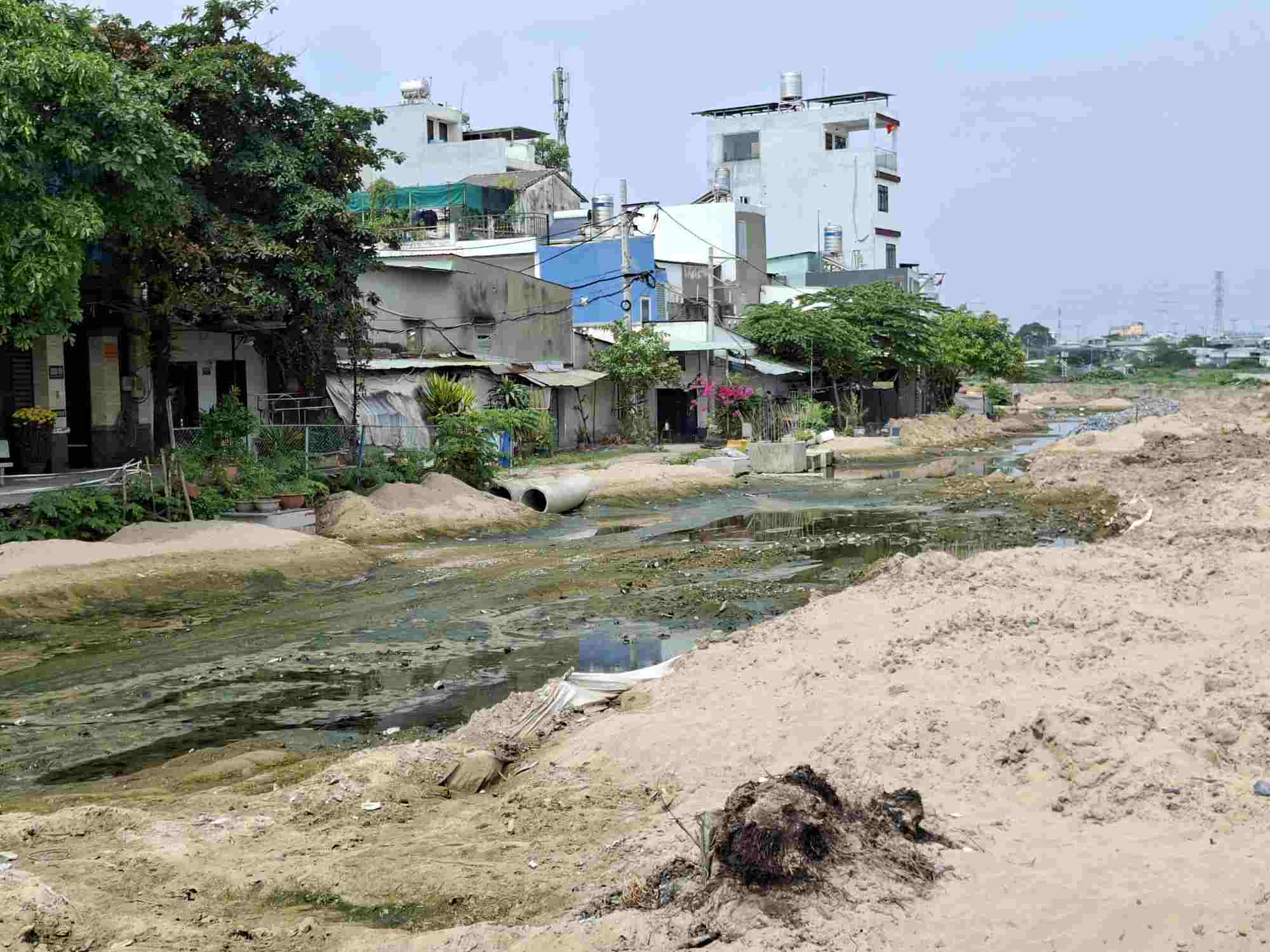 Đoạn đường ven kênh thi công dang dở, đọng nước gây ô nhiễm.  Ảnh: Minh Quân