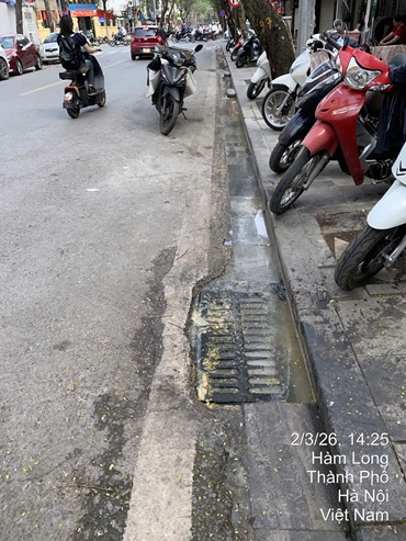 Nước trà qua vỉa hè ra cống tại đường Hàm Long. Ảnh: Nhi Dung