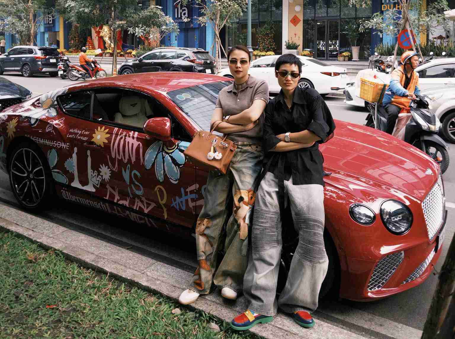 Đàm Thu Trang (bên trái) chụp hình bên siêu xe cùng stylist Pông Chuẩn. Ảnh: NVCC.