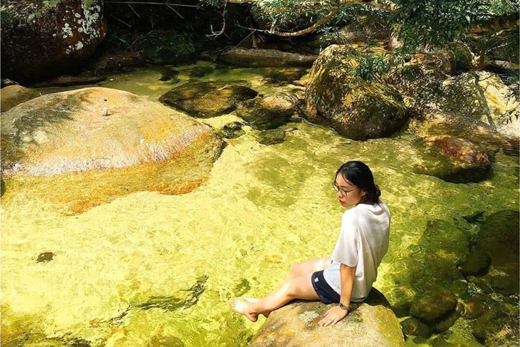 Nước ở Thác Ba Tia mang sắc vàng đặc trưng, trong veo, có thể nhìn rõ những viên đá dưới lòng suối. Ảnh: Thu Hoài
