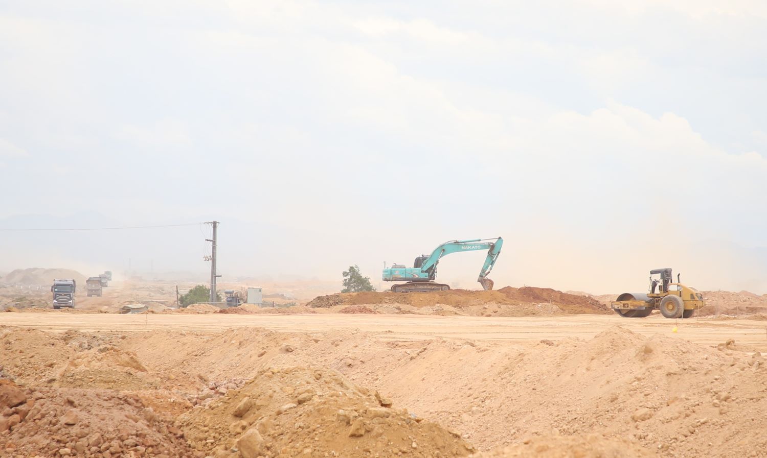 Để đẩy nhanh tiến độ, nhiều xe máy được huy động thi công trong thời tiết nắng gắt, gió mạnh nên bụi phát tán nhiều. Ảnh: Hưng Thơ