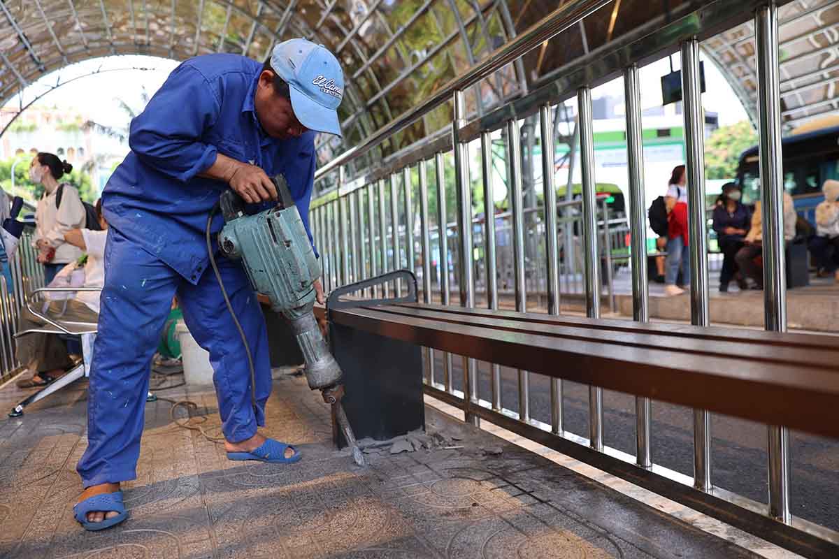 Các công nhân khẩn trương kiểm tra, sửa chữa ghế ngồi, đá vỉa hè bị chênh, vỡ tại khu vực chờ xe buýt. Ảnh: Như Quỳnh